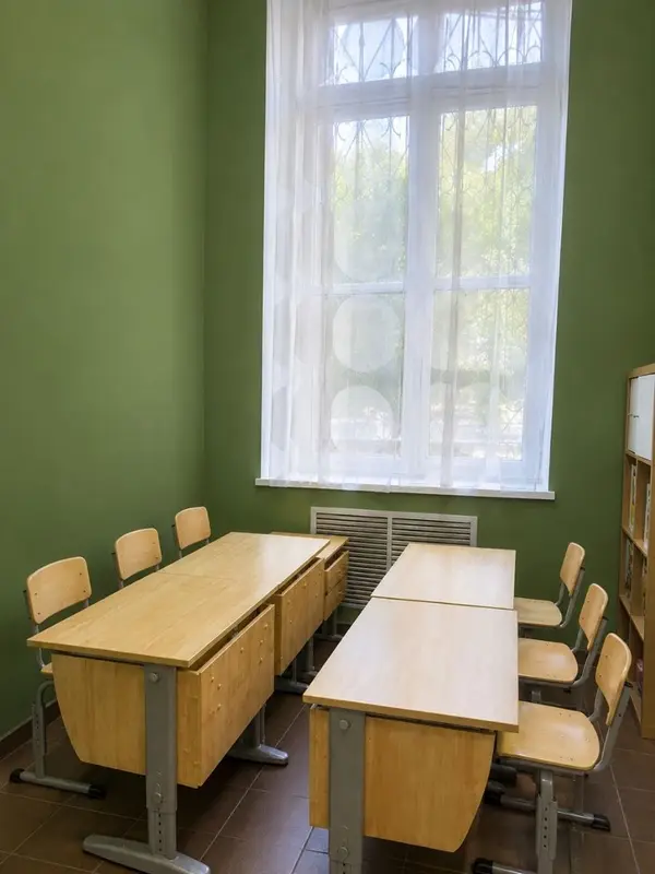 Класс с партами и детскими стульями у большого окна